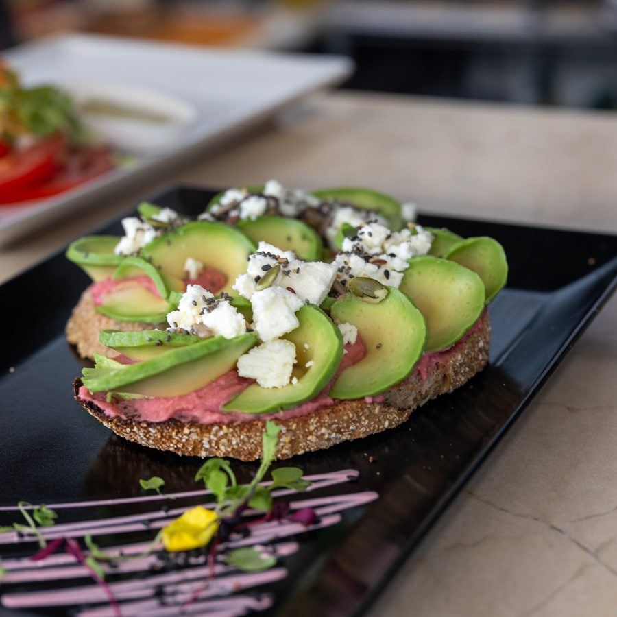 Avocado toast with feta on a slate plate.