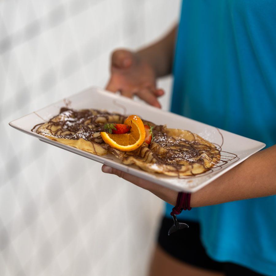Crêpes with chocolate sauce, orange and strawberry, carried out to a table.