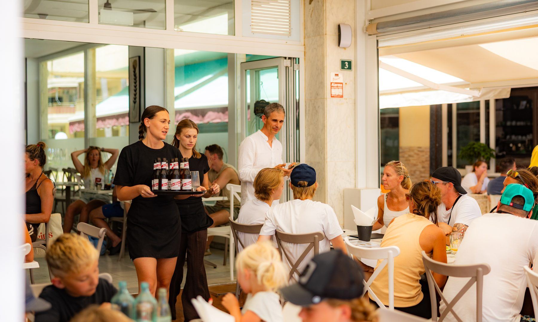 A Café Nomad server bringing a tray of smoothies to a full table of guests.
